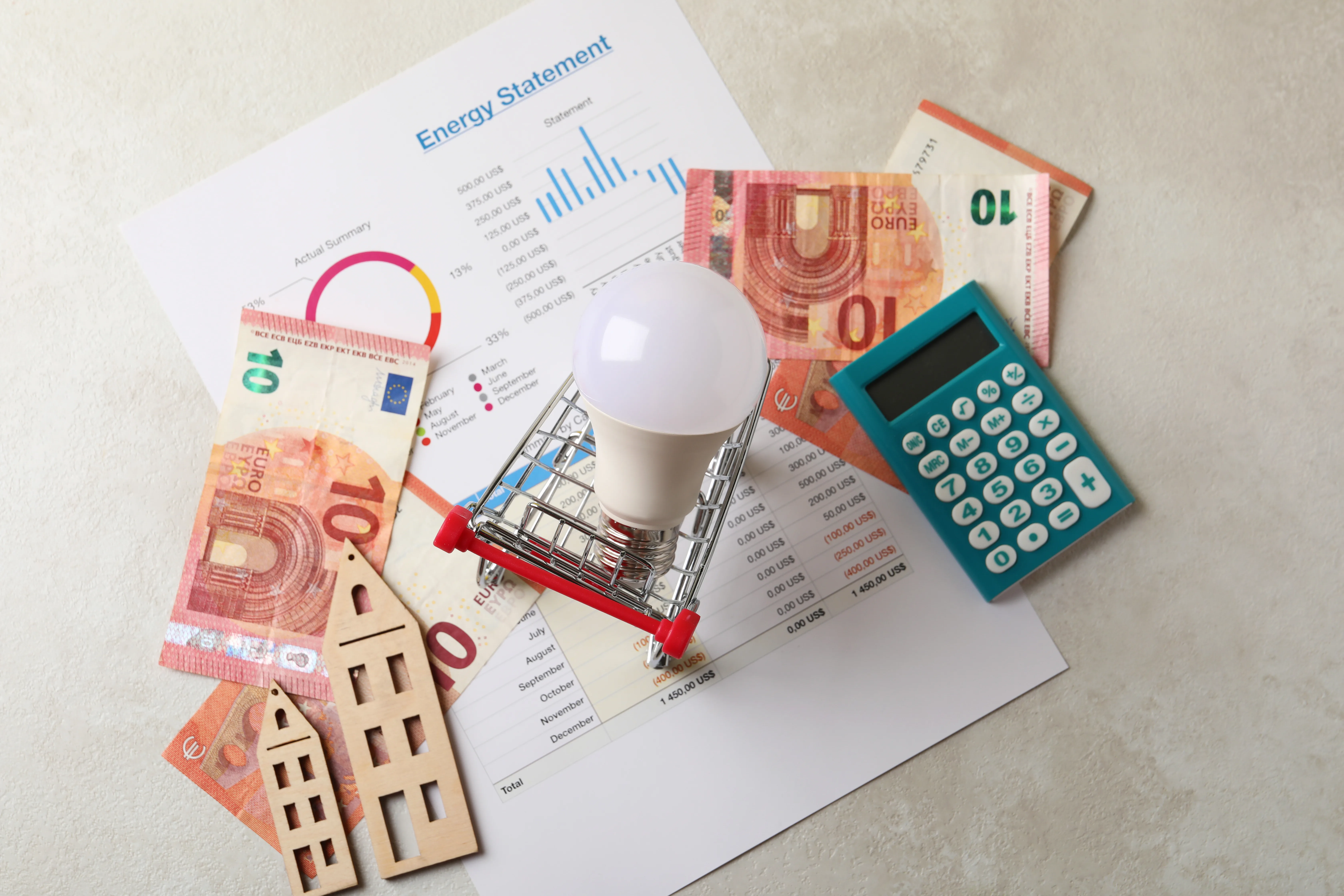 Calculatrice et ampoule sur un bilan énergétique avec des euros, symbolisant l'autoconsommation solaire