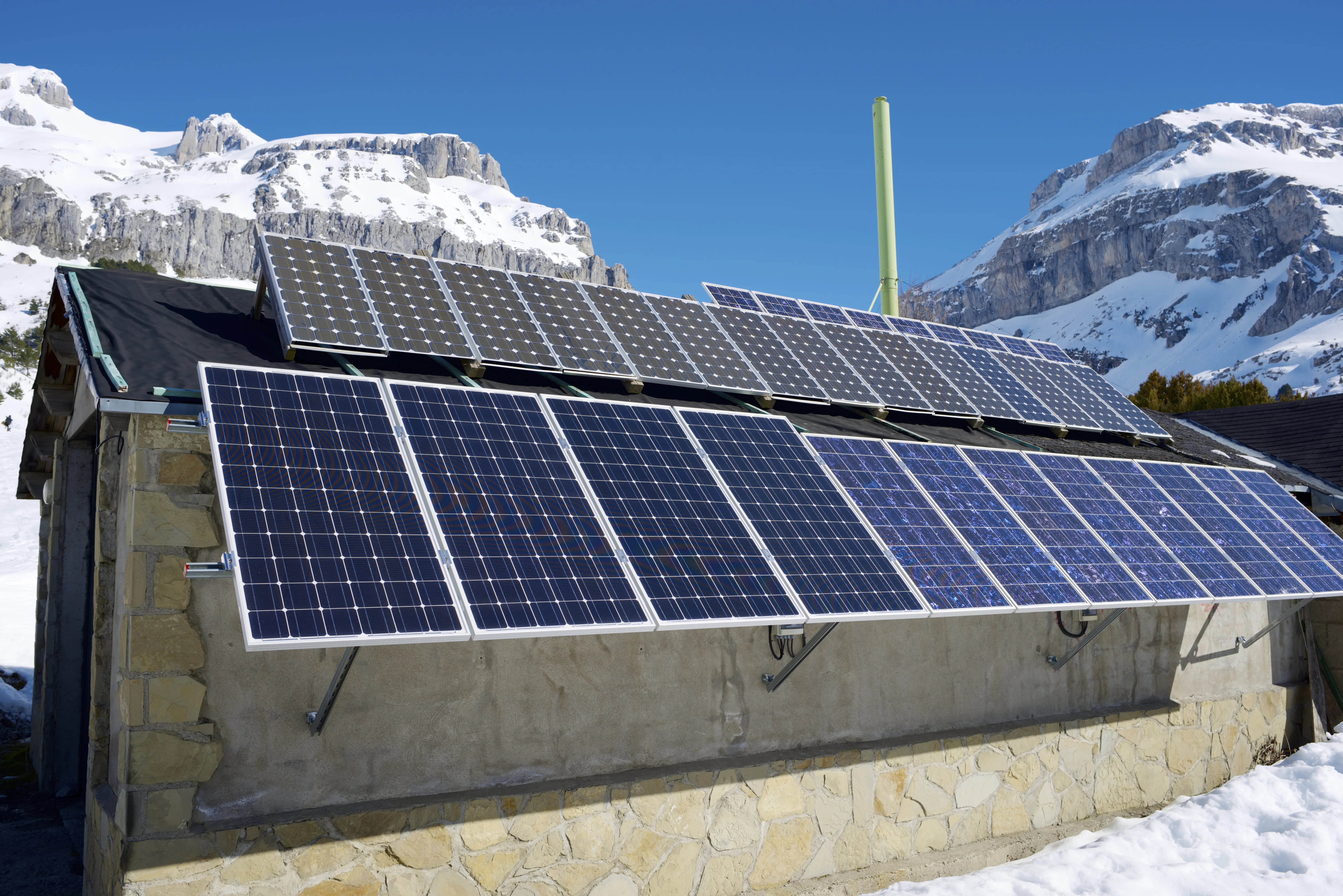 Installation de panneaux photovoltaïques sur un toit avec des montagnes enneigées en arrière-plan