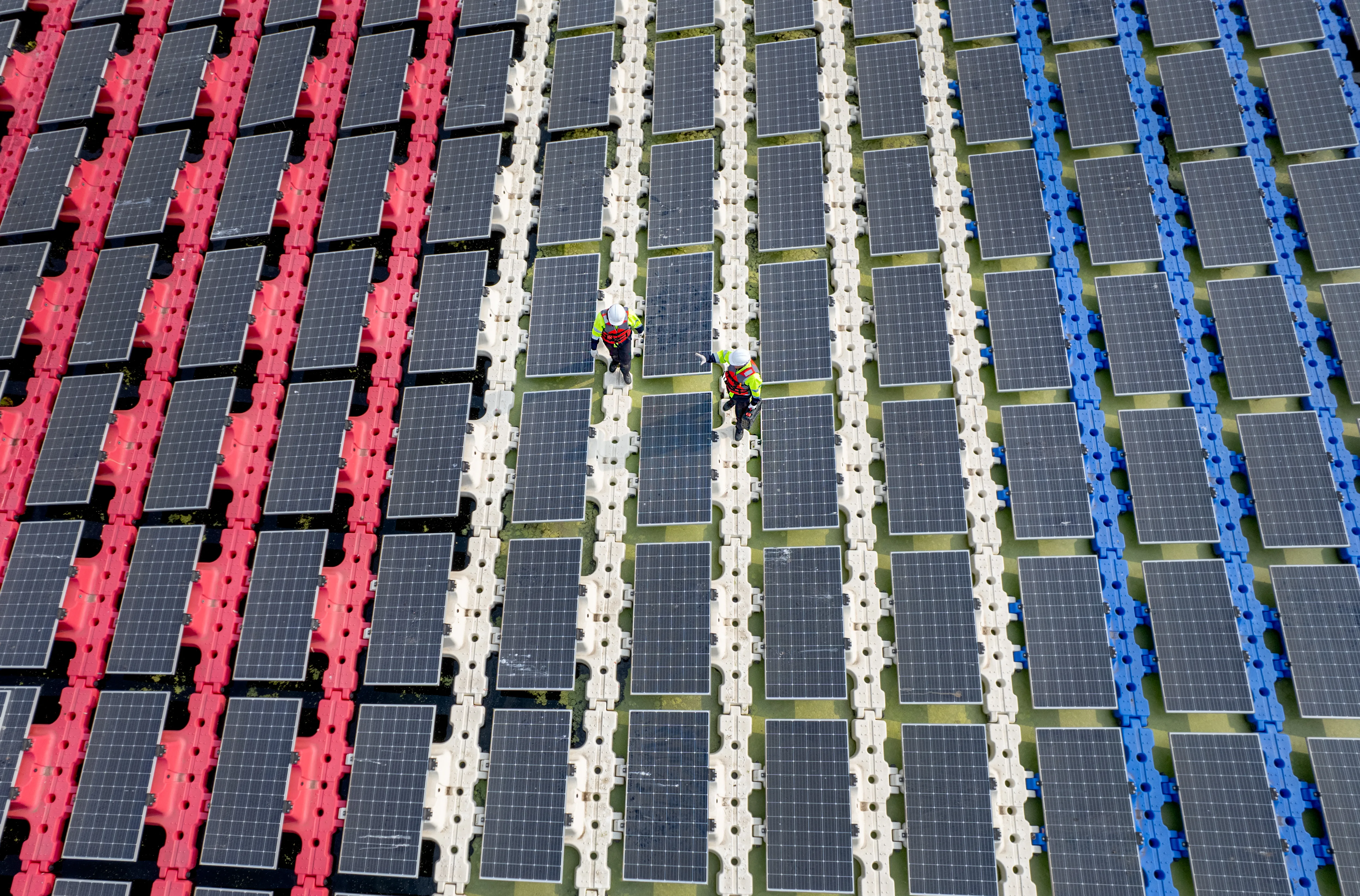 Deux techniciens installent des panneaux photovoltaïques sur une surface colorée