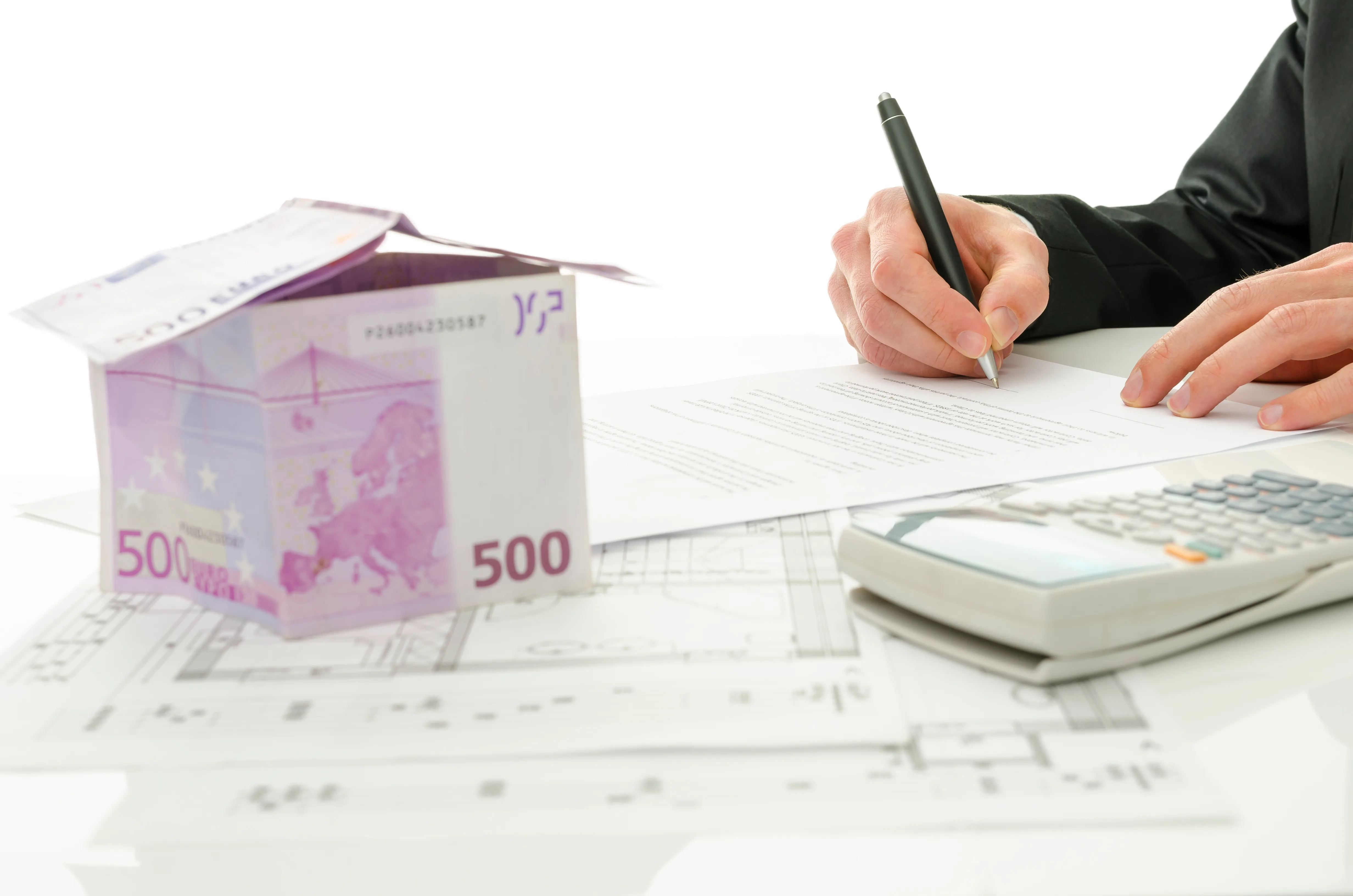 Une personne signe des documents avec des billets de 500 euros et une calculatrice sur un plan