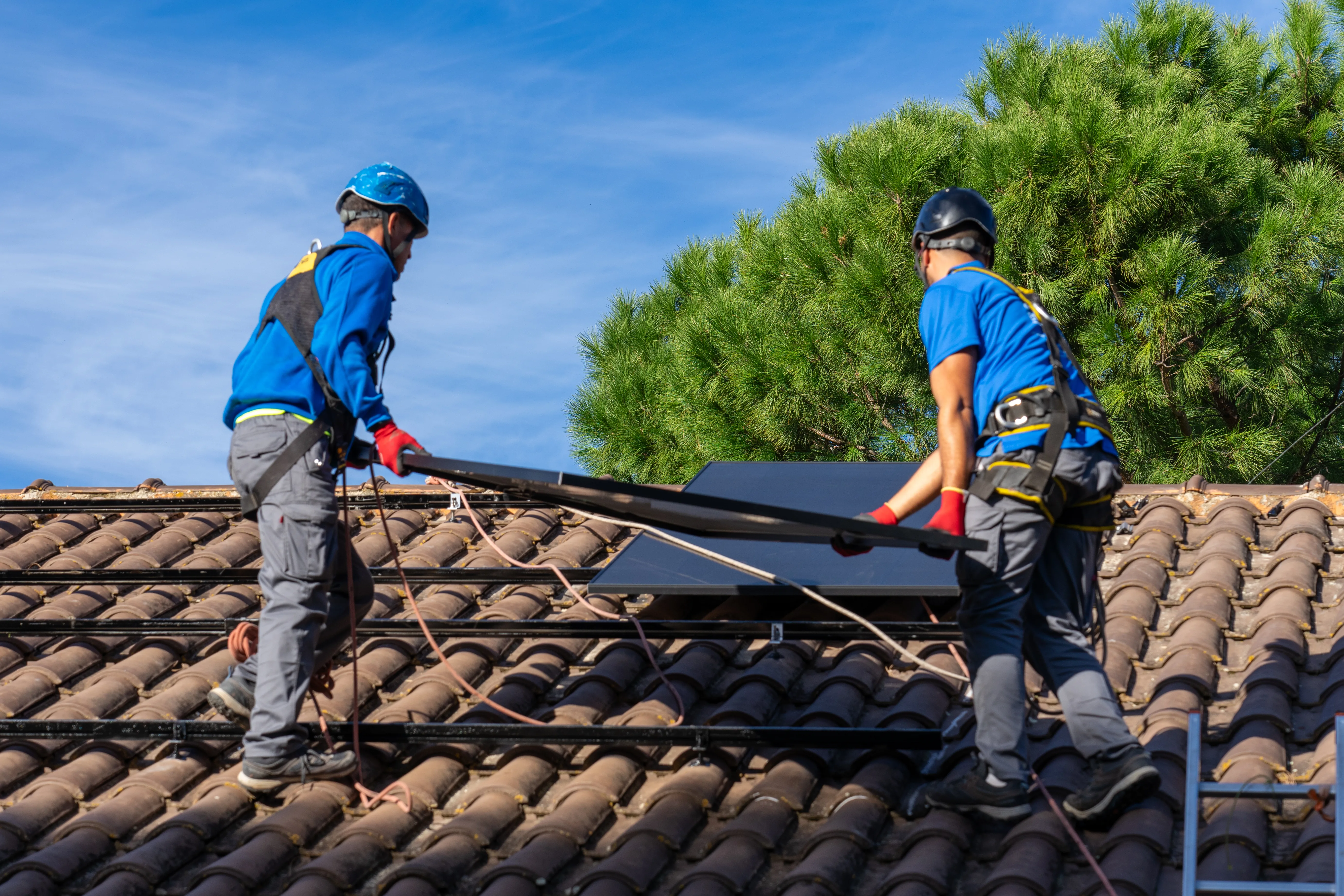 Installation de panneaux solaires sur un toit par deux techniciens