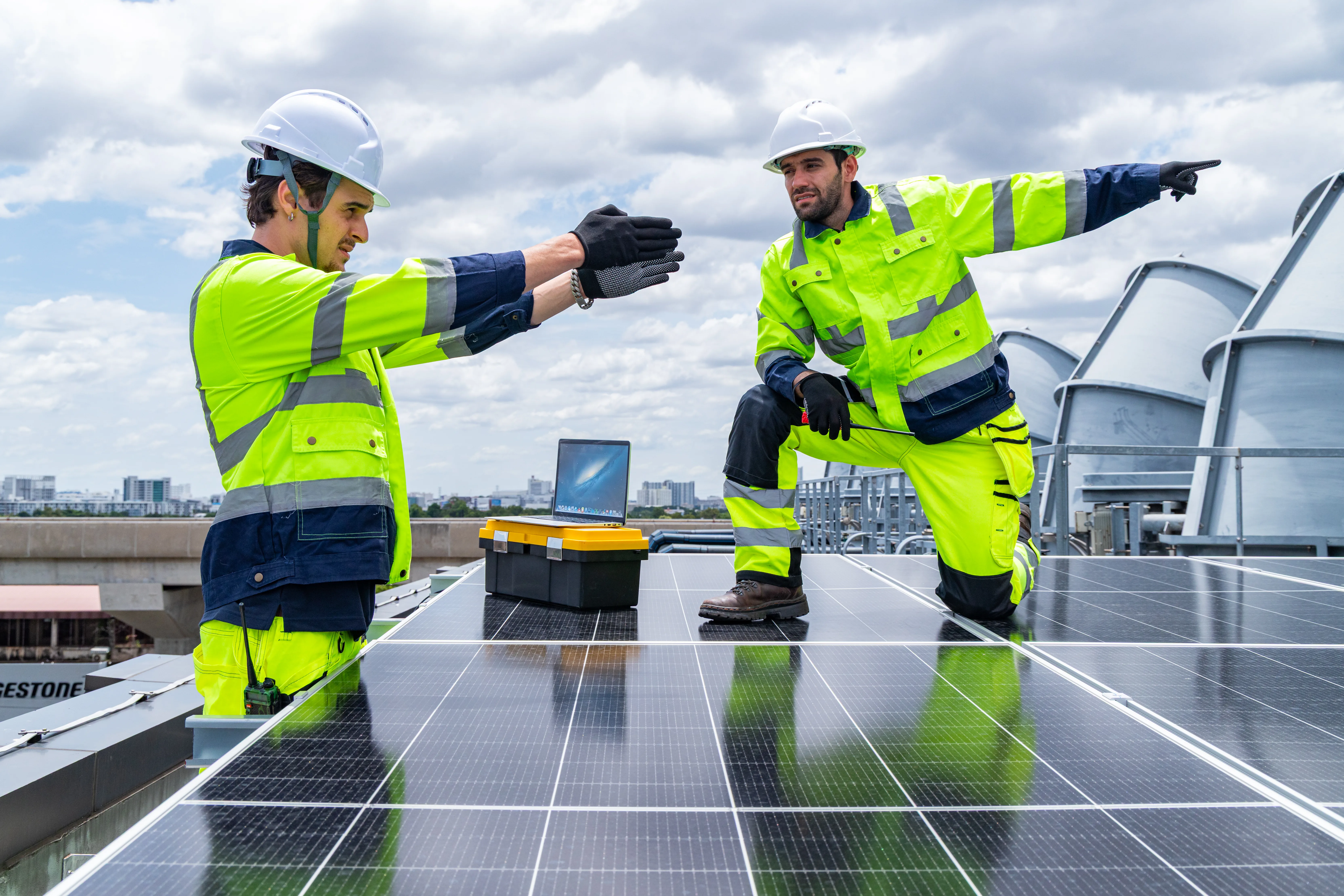 Techniciens installant des panneaux photovoltaïques sur un toit, supervisant la pose
