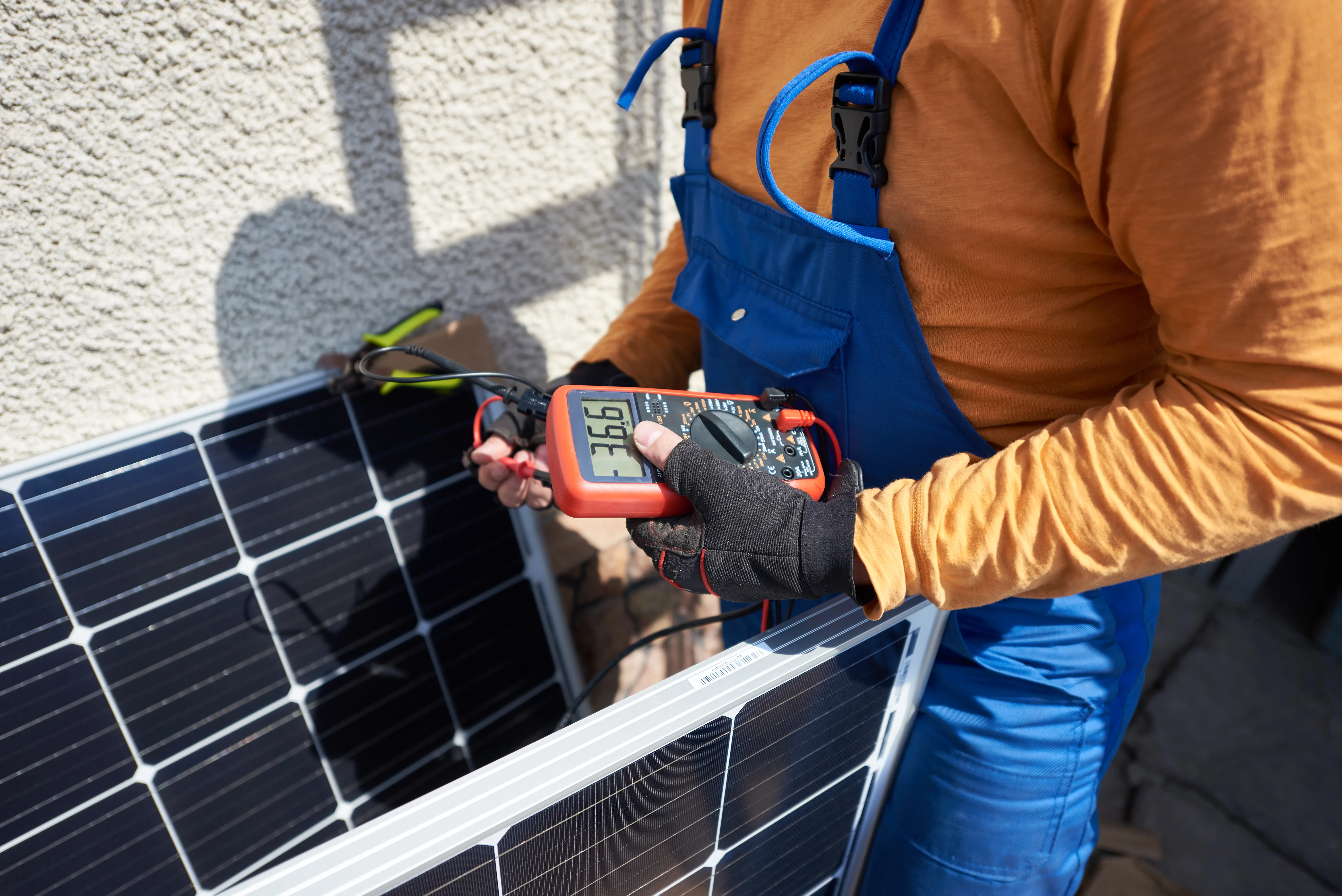 Technicien vérifiant un panneau solaire avec un multimètre lors de l'installation photovoltaïque