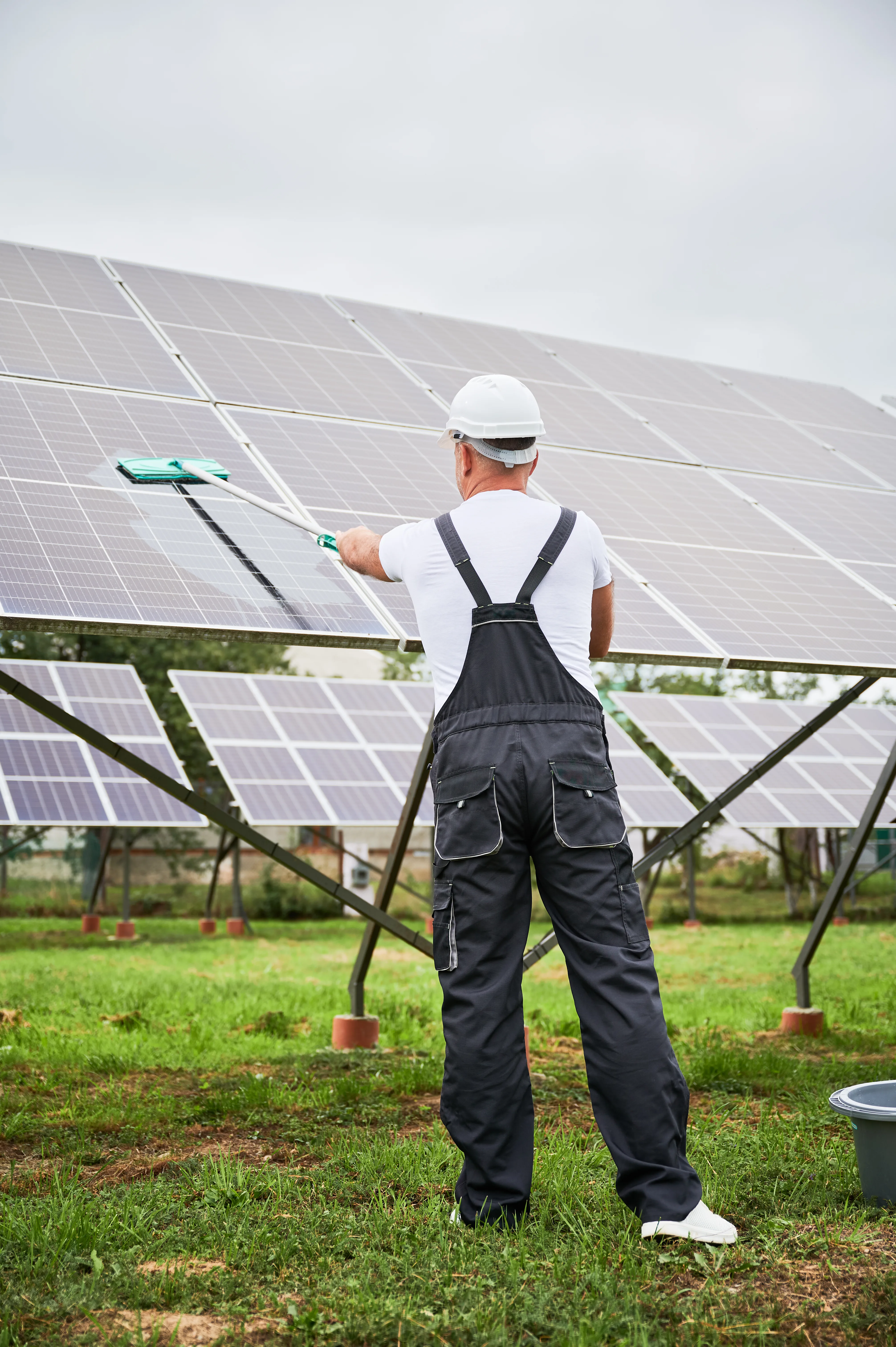 Technicien nettoyant des panneaux solaires sur une installation photovoltaïque au sol
