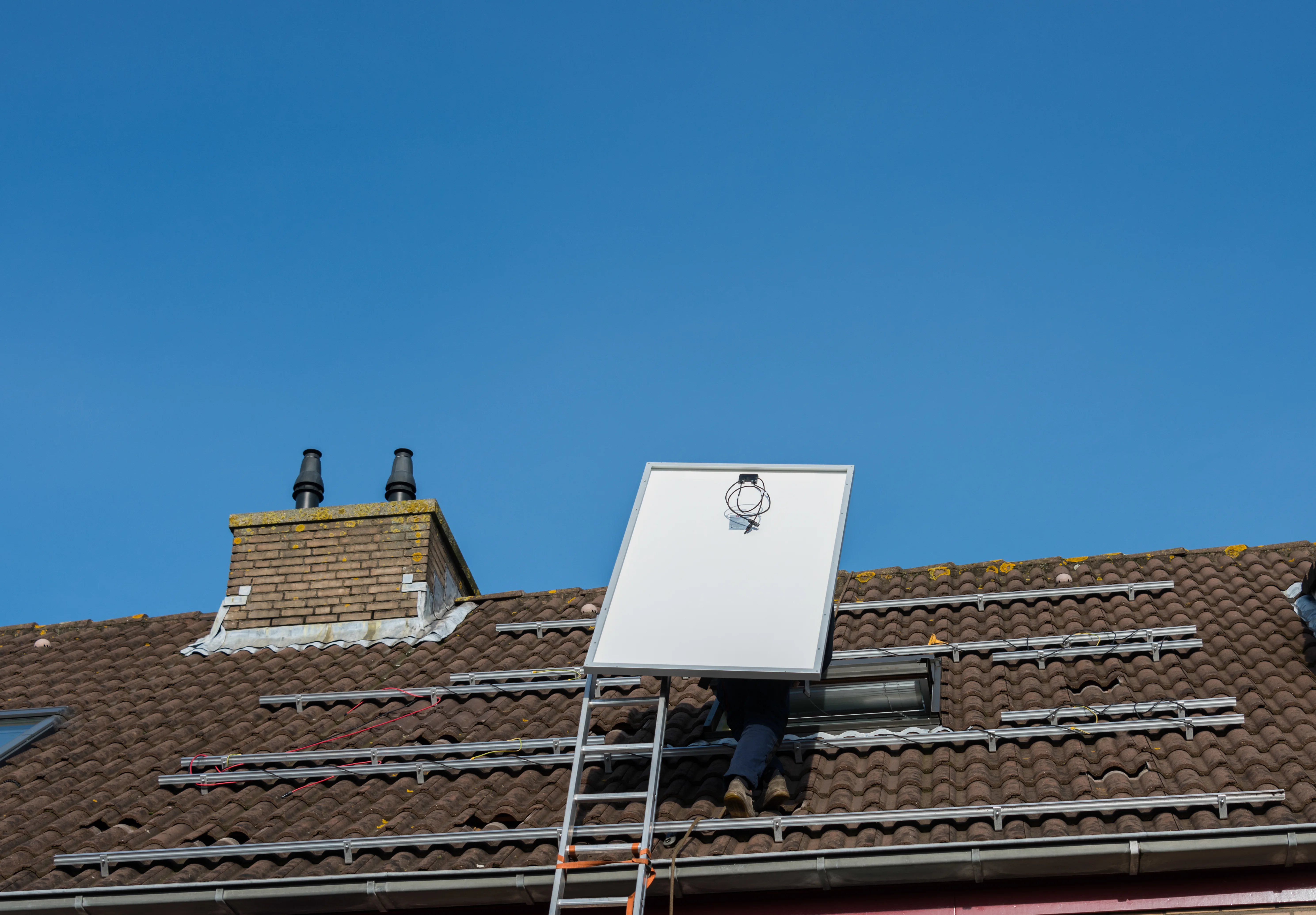 Installation de panneaux photovoltaïques sur un toit en pente sous un ciel bleu clair