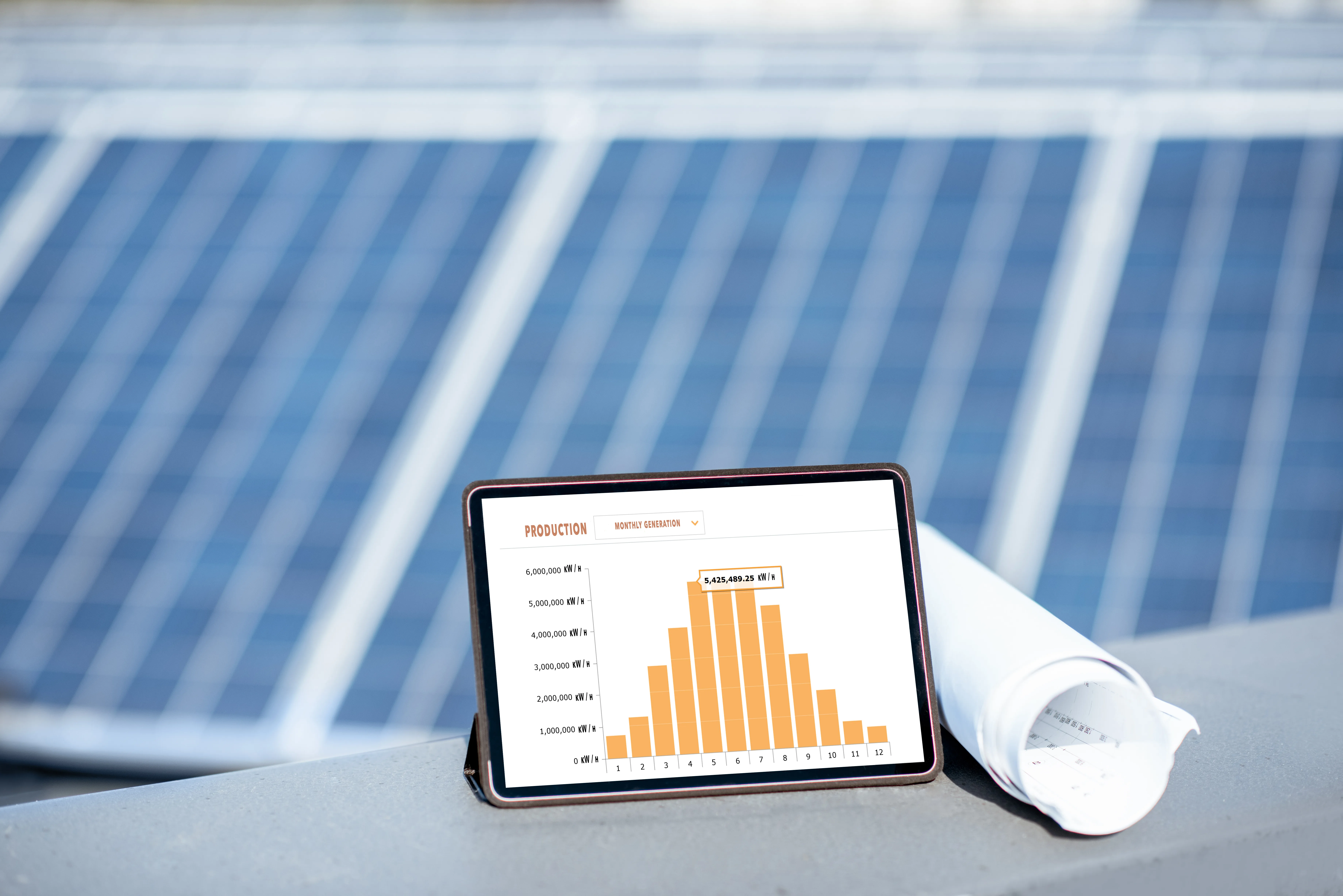 Graphique de production solaire sur une tablette, avec panneaux photovoltaïques en arrière-plan
