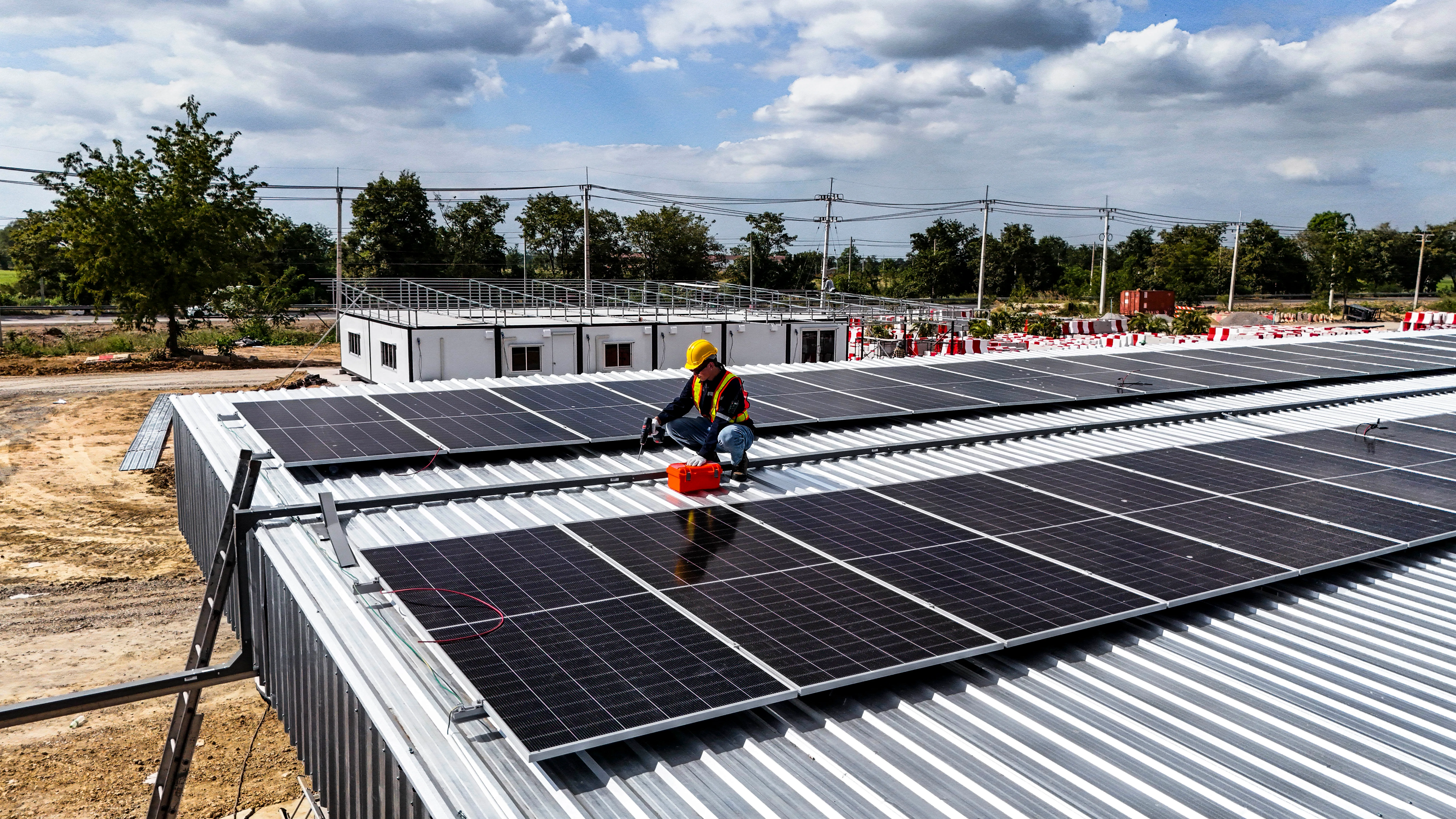 Installation de panneaux photovoltaïques sur un toit, avec un technicien en pleine action