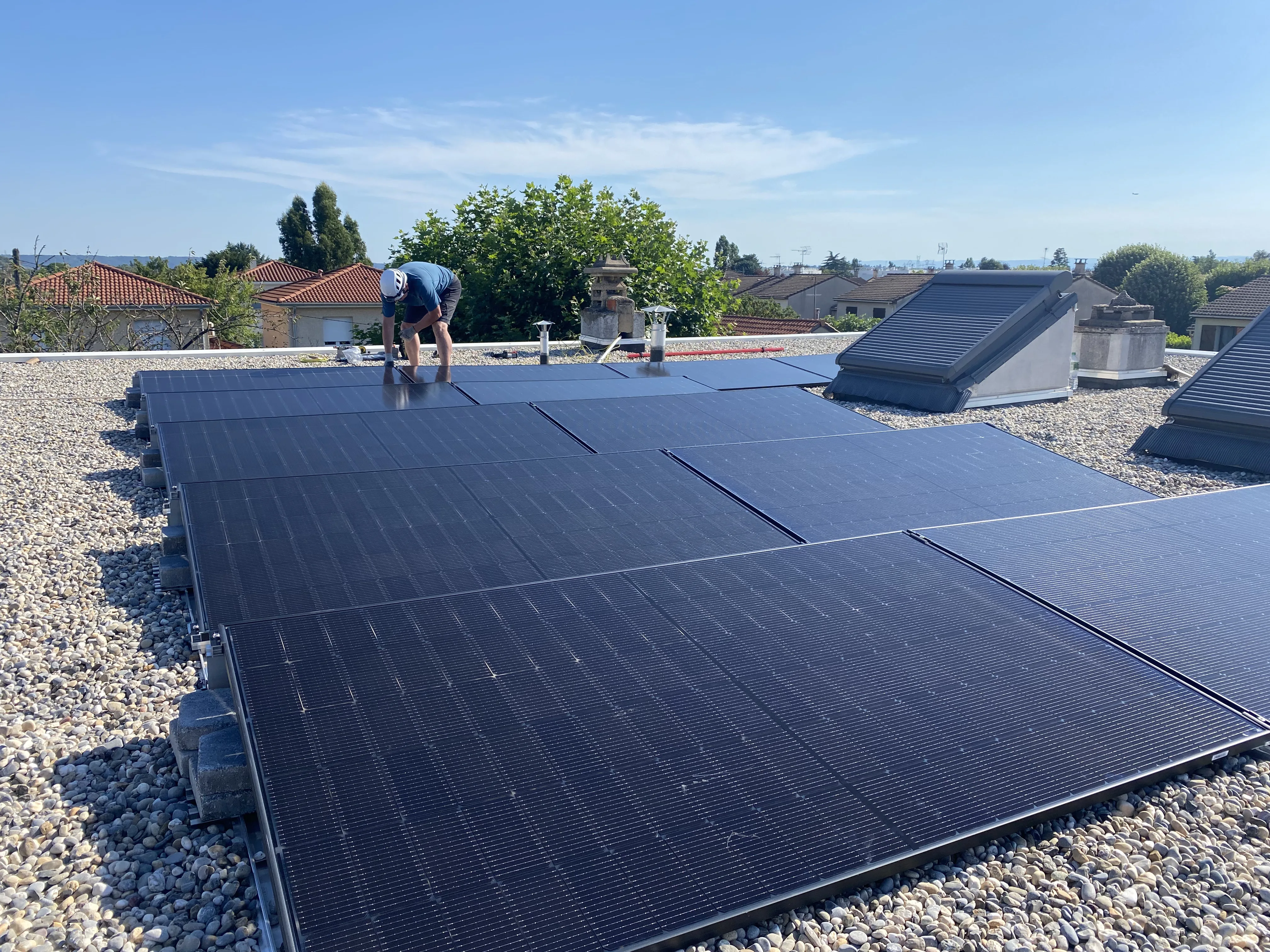 Installation de panneaux photovoltaïques sur une toiture plate, avec un technicien en action