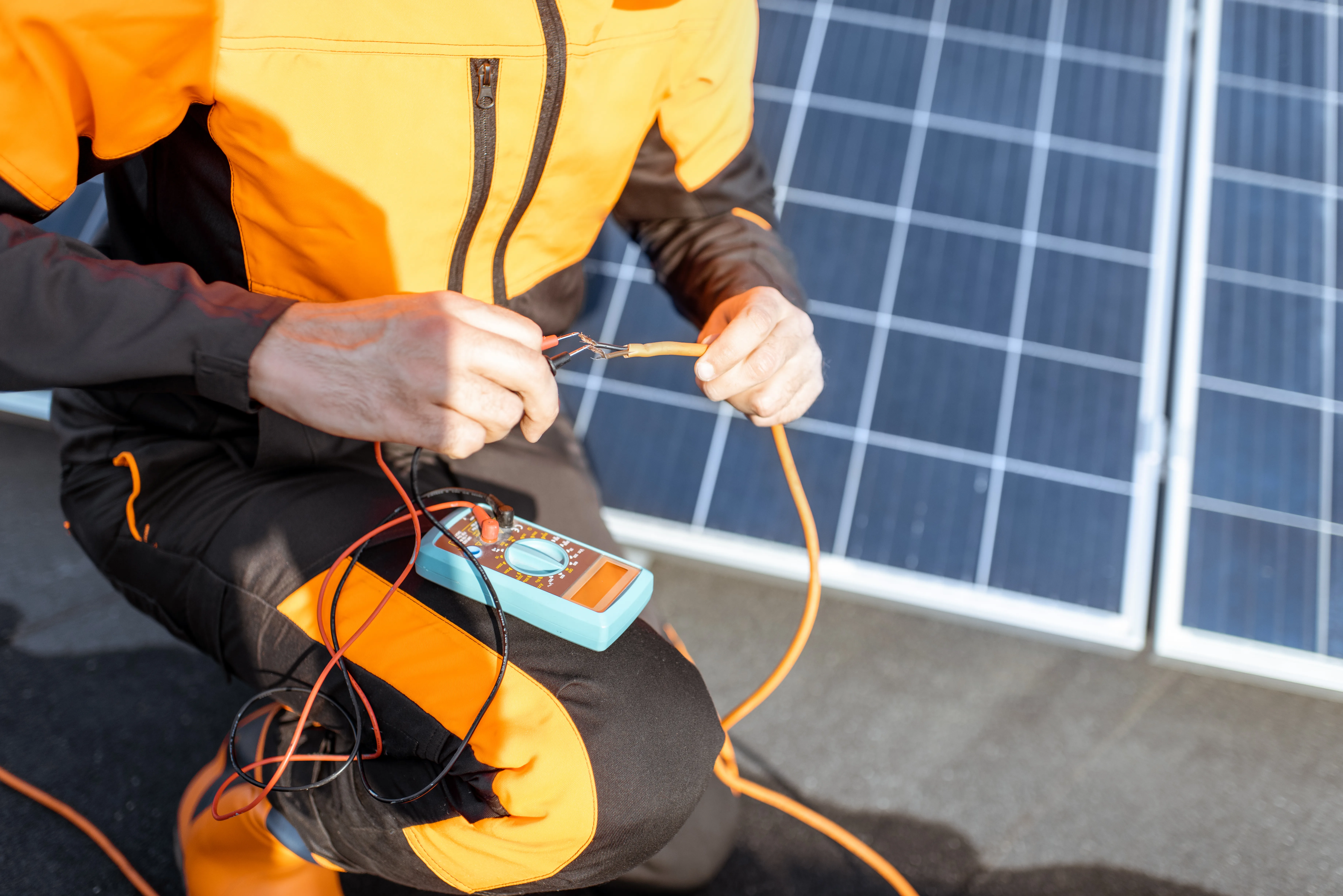 Technicien vérifiant le système photovoltaïque avec un multimètre, panneaux solaires en arrière-plan
