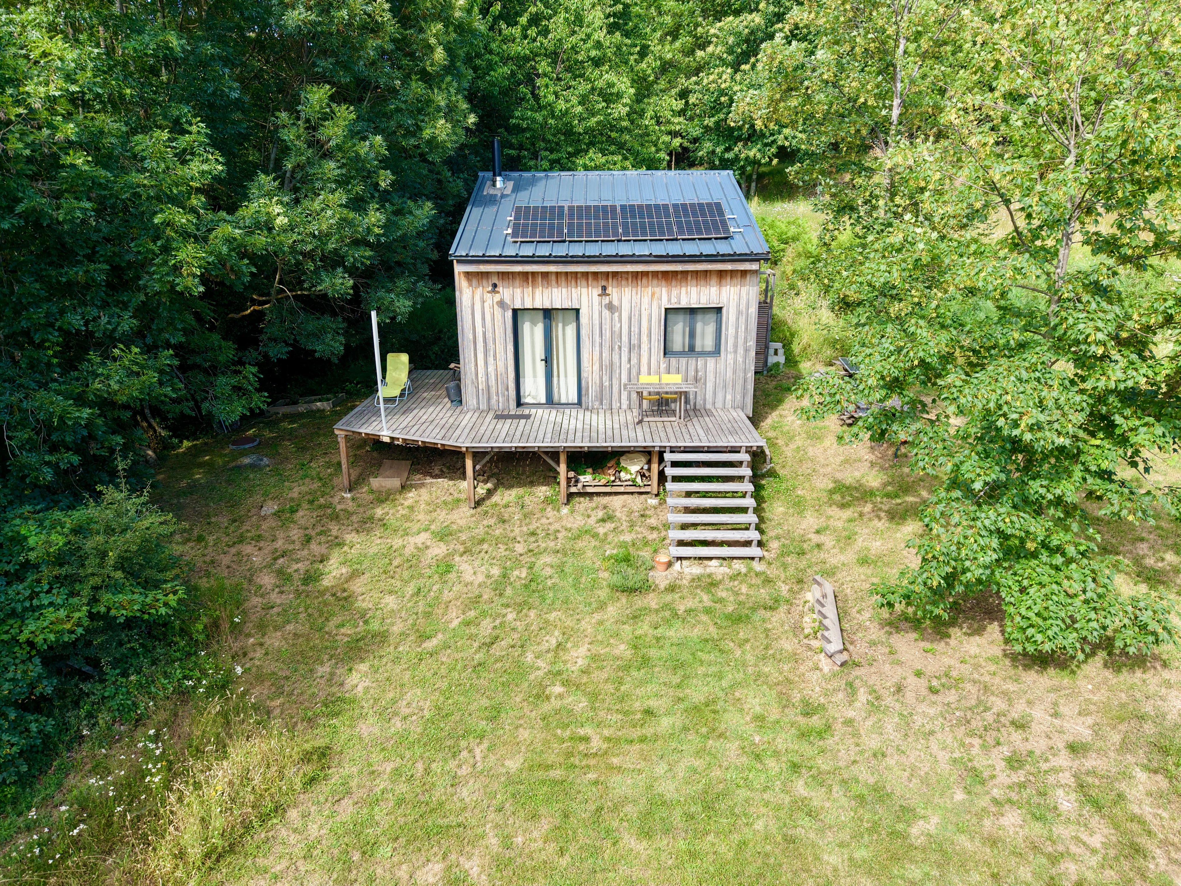 Maison en bois avec panneaux photovoltaïques sur le toit, installée en milieu naturel